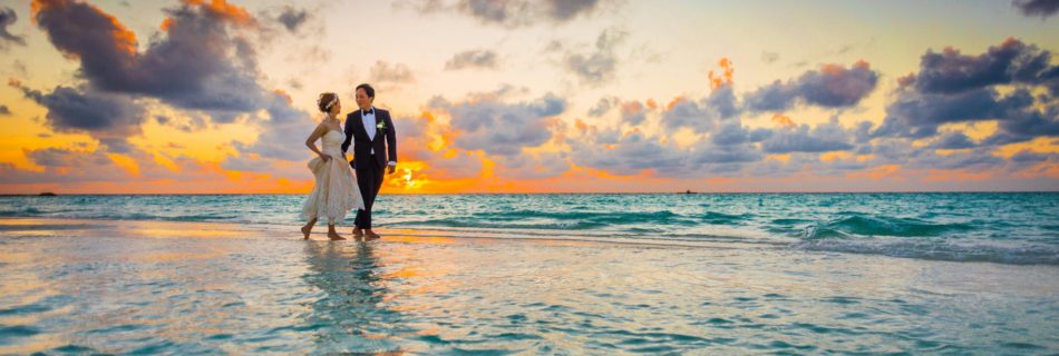 man and woman walking of body of water